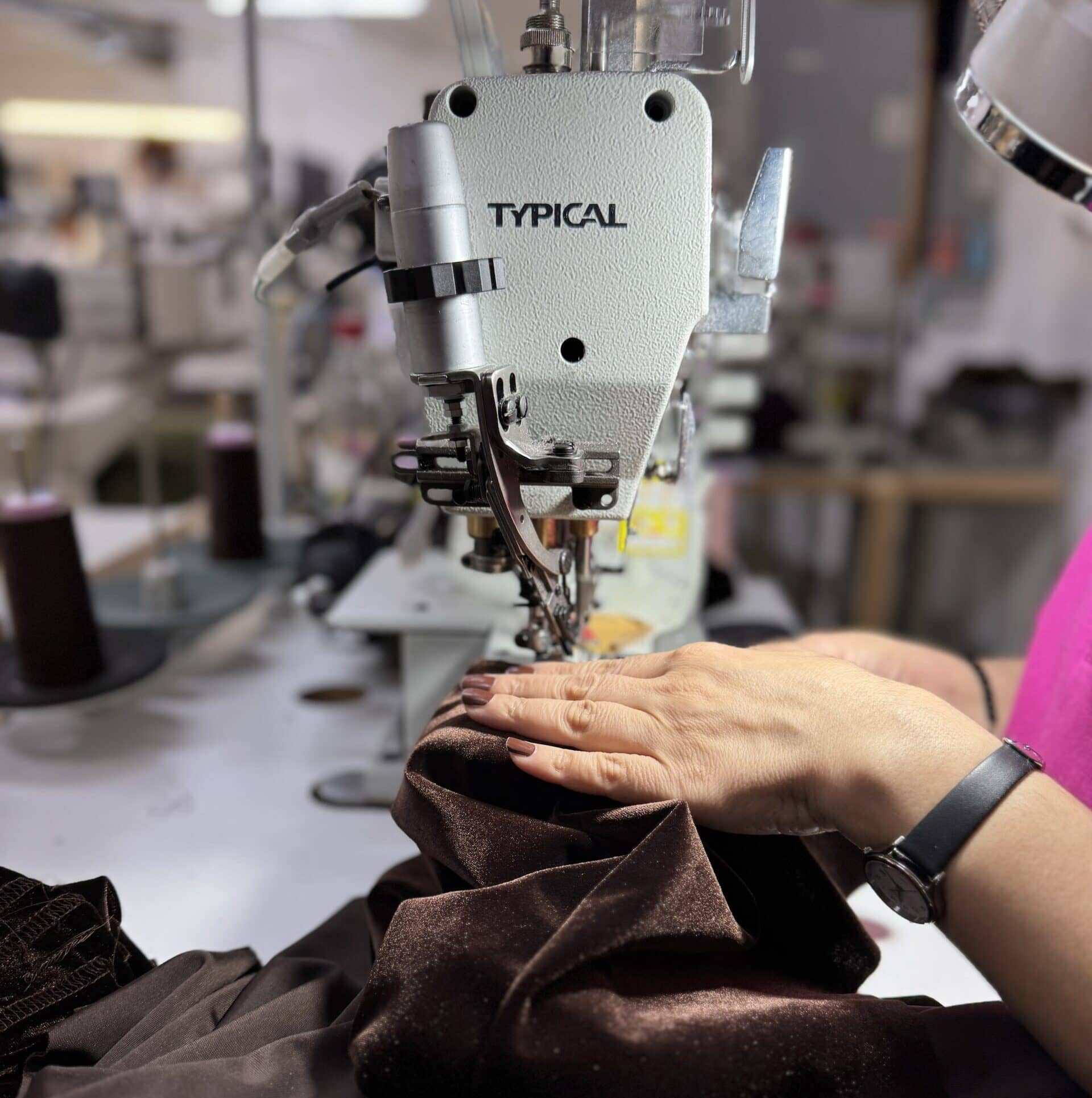 Eine Person näht braunen Stoff mit einer Industrienähmaschine